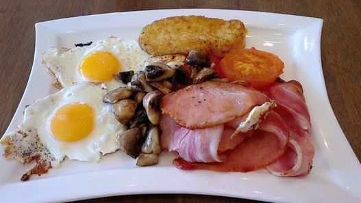 Foto irski doručak s prženim jajima, hash Brownsom i pečenim rajčicama